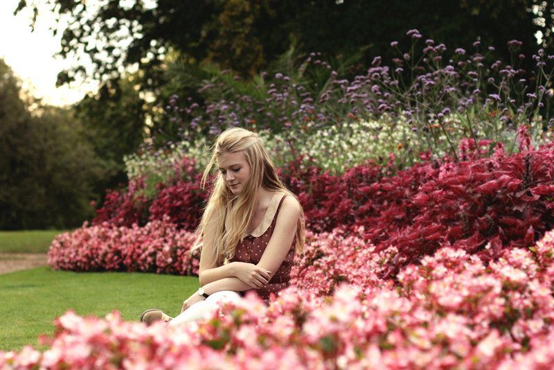 young woman outside kneeling down by flowers