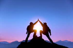 two people standing at top of pinnacle