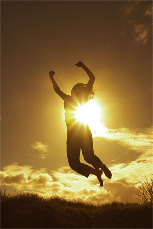 woman jumping with sun behind her