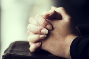 hands folded in prayer on Bible