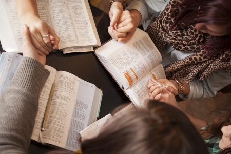 women holding hands with Bibles open