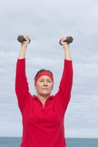 mature woman holding weights above head