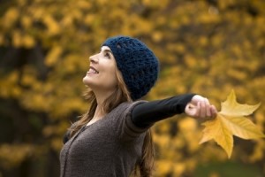 woman with arms raised outside in fall