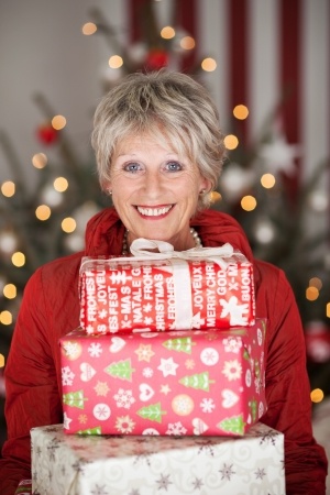 woman holding presents in front of Christmas tree