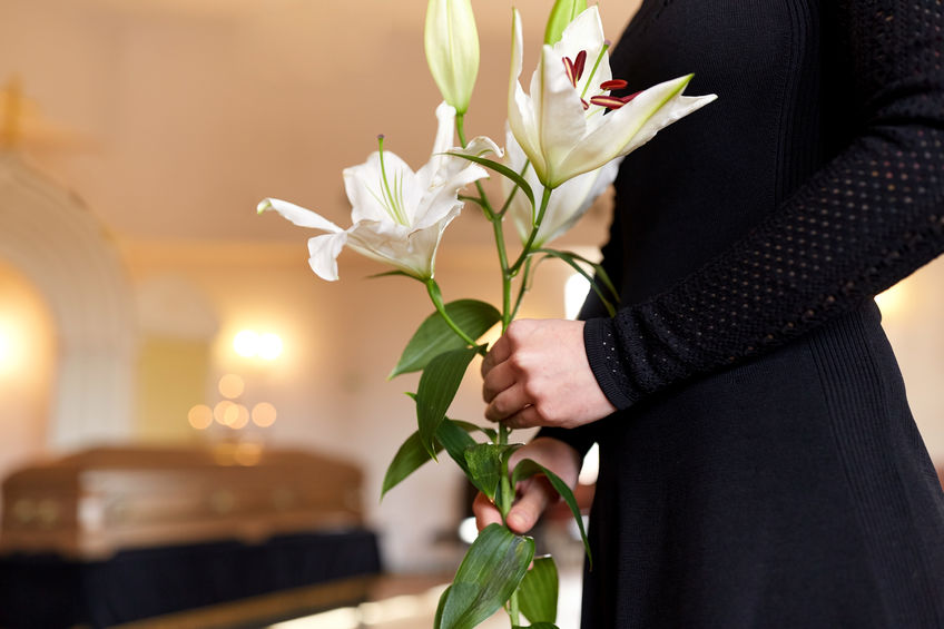 close up of woman with lily flowers at funeral